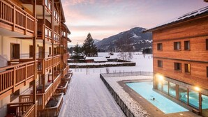 A hotel with multiple balconies, a swimming pool, and a snowy landscape with mountains in the background. - Wifi, swimming pool, terrace, balcony, tv, ski locker, 43-61m², Samoëns (Samoëns)