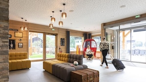 A modern lobby with a large sofa, a red seating area, and a suitcase on the floor. - Wifi, swimming pool, terrace, balcony, tv, ski locker, 34-44m², Samoëns (Samoëns)
