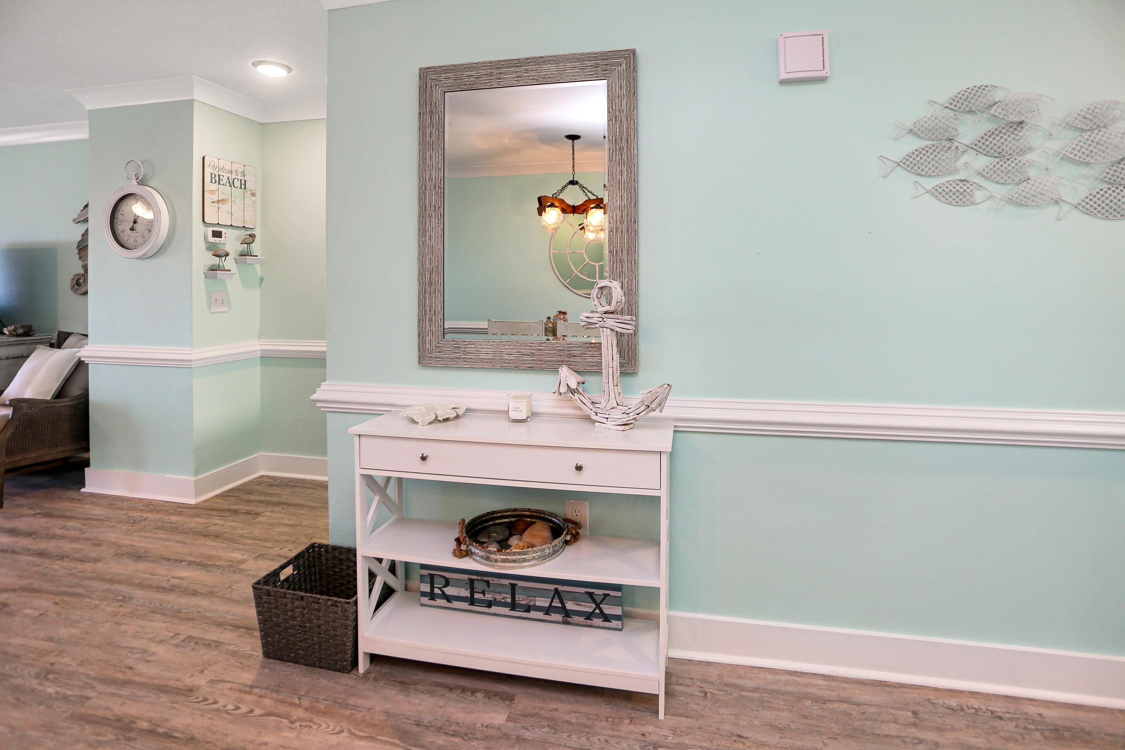 Une salle de bain avec un meuble-lavabo, un miroir, un lustre et des éléments décoratifs sur les murs.