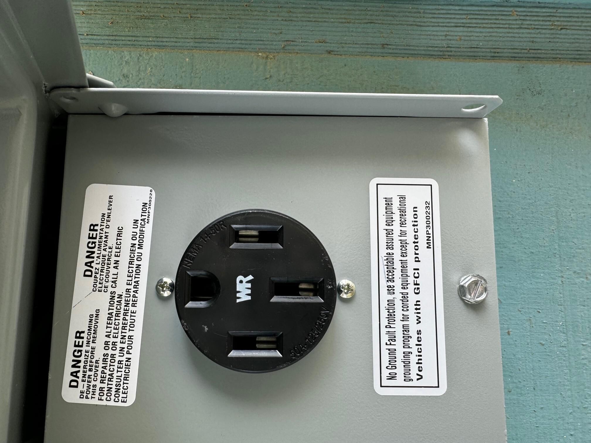 A utility box with a black electrical component and warning labels.