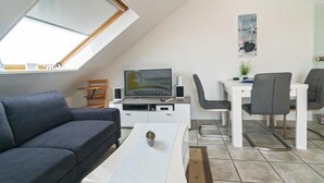 Een moderne woonkamer met een bank, een salontafel, een televisie en een eethoek met stoelen en een tafel.