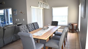 A dining area with a wooden table, grey upholstered chairs, and a chandelier.