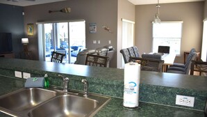 A kitchen with a granite countertop, stainless steel sink, and a paper towel dispenser.
