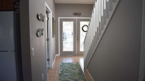 A hallway with a tiled floor, a rug, and a door with a wreath.