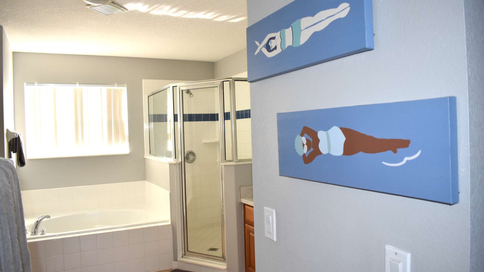 A bathroom with a bathtub, a glass shower enclosure, and two wall-mounted signs.