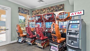 Um quarto com quatro máquinas de jogos de corrida de fliperama e um caixa eletrônico.