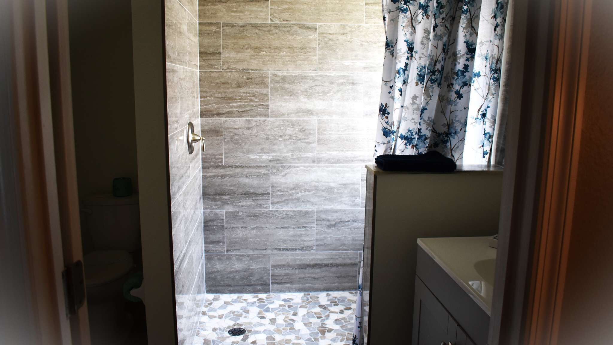 A bathroom with a shower area, tiled walls, and a sink.