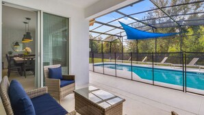 Une terrasse couverte avec une piscine, des meubles en osier et un coin repas offrant une vue sur la piscine.