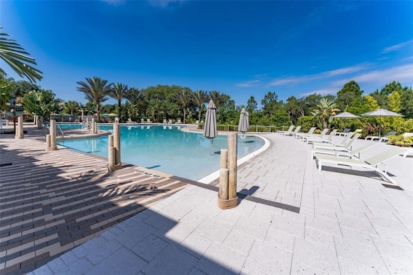 Relax by the pool surrounded by lush greenery and lounge under shaded umbrellas.
