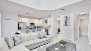 A modern living room with a sofa, coffee table, and a view into the kitchen.