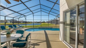 Un espacio al aire libre cubierto con piscina, sillas y una mesa.