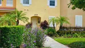 A yellow building with the number 2779, surrounded by lush greenery and palm trees.