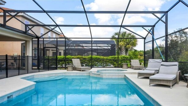 Une piscine extérieure dotée de chaises longues et d’une structure en verre.