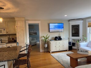 Cozy living space with a kitchen, dining area, and comfortable seating, featuring a fireplace and large window.