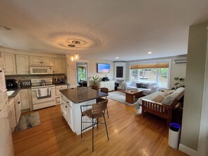 Enjoy cooking and relaxing in this open-plan kitchen and living area featuring a central island, oven, and comfortable seating.