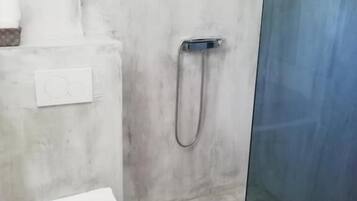 Egy fürdőszoba, amelyben WC, zuhanyzó és üvegfallal elválasztott zuhanyzósarok található.