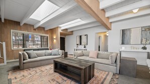 A modern living room with two sofas, a coffee table, and a patterned rug.