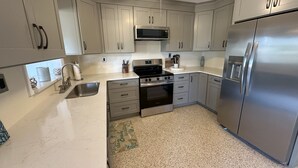 A modern kitchen with white cabinets, stainless steel appliances, and a granite countertop. - 2 Minutes to Downtown Crystal River, Large Fenced Yard, Boat Ramp, Pets OK ! (Crystal River)