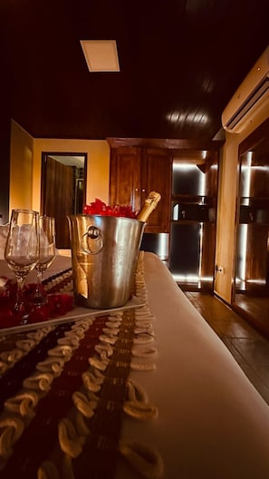 A dining area with a table set for two, a metal bucket, and a bottle of champagne. - Pousada Pedras Secas (Fernando de Noronha)