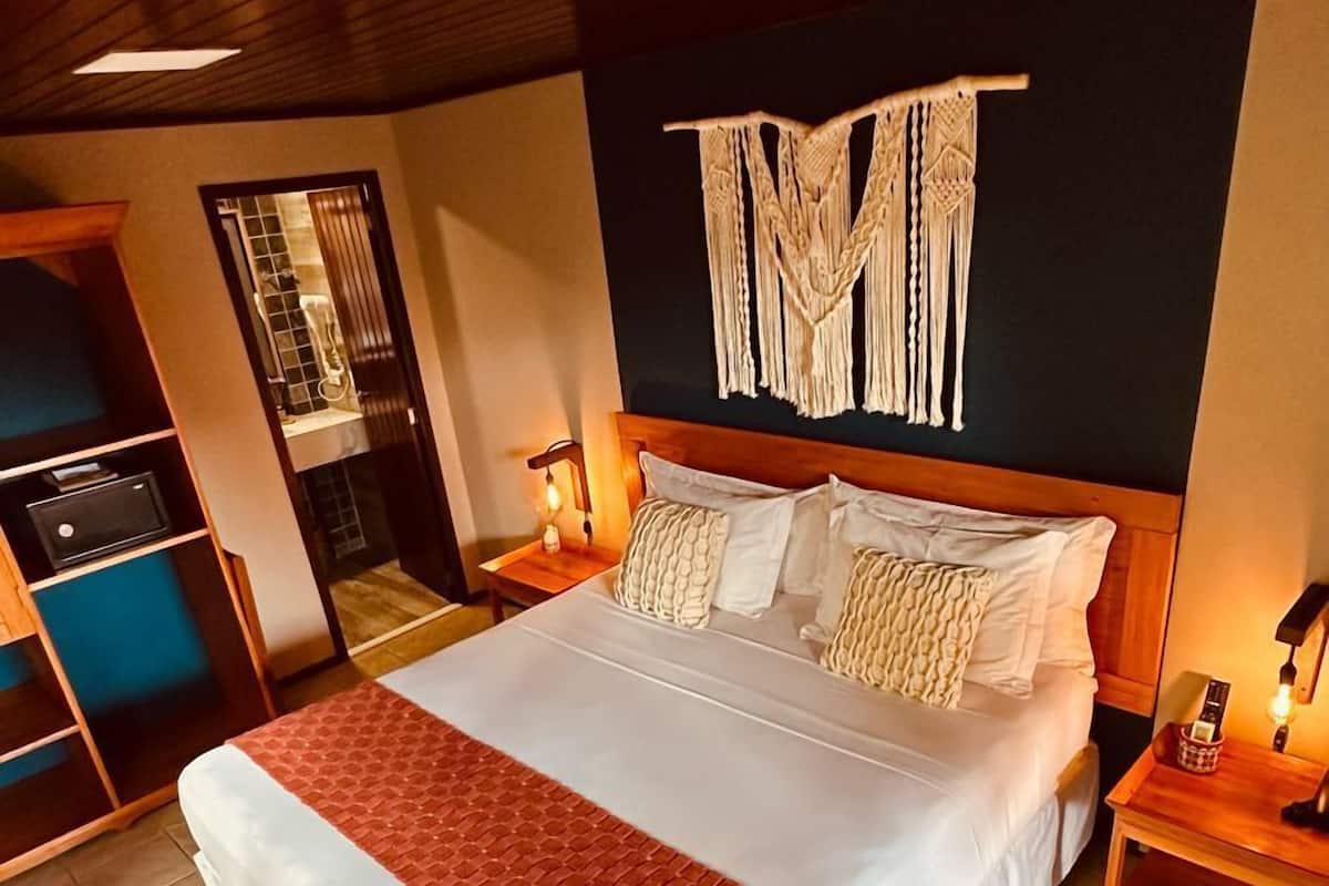 Ein geräumiges Schlafzimmer mit einem großen Bett, einem Holzkopfstück und einer Wanddekoration aus Makramee.