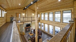 A spacious cabin with a high ceiling, wooden walls, and large windows. - Large River front cabin overlooking Glover River (Broken Bow)
