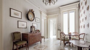 Une pièce spacieuse, dotée d’une grande commode en bois, d’une table à manger avec des chaises et d’un lustre.