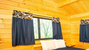 A wooden cabin room with a bed, two windows with curtains, and a ceiling light. - 126) Zonetail Log Cabin. Close to Hocking Hills State Park and more! (Logan)