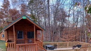 A wooden cabin with a porch, a deck, and a table and chairs. - 126) Zonetail Log Cabin. Close to Hocking Hills State Park and more! (Logan)