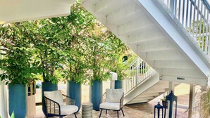 An outdoor seating area with two chairs and potted plants, a brick floor, and a staircase. - Southwinds #9 for 3, King Studio Steps to Beach (Hollywood)