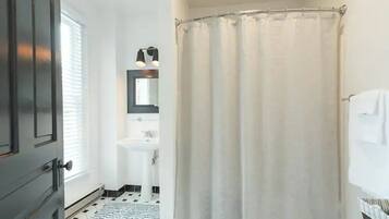 A bathroom with a shower curtain, a sink, and a mirror.