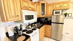 A modern kitchen with wooden cabinets, a white stove, a stainless steel refrigerator, and a microwave. - Southwinds #4 for 2, Steps to Beach & Boardwalk (Hollywood)