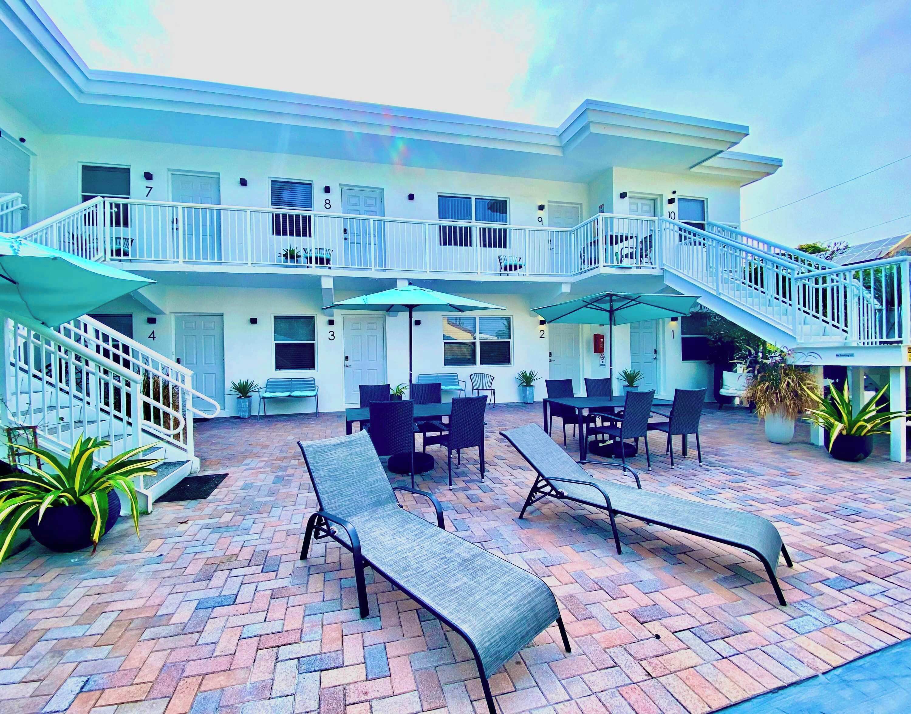 A hotel with a patio area featuring outdoor seating and a staircase leading to the upper floors.