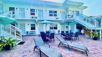 A hotel with a patio area featuring outdoor seating and a staircase leading to the upper floors.