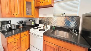 A compact kitchen with wooden cabinets, a stove, a microwave, and a coffee maker. - Hollywood Boardwalk Studio Fully Equipped Kitchen (Hollywood)