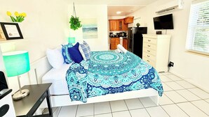 A bedroom with a bed, bedside table, lamp, and a view into the kitchen. - Hollywood Boardwalk Studio Fully Equipped Kitchen (Hollywood)