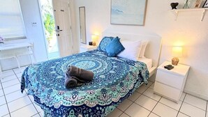 Ein Schlafzimmer mit einem gestreiften Bettbezug, einem Nachttisch mit Lampe und einem Fenster mit Jalousien.