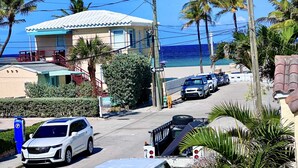 Eine Küstenstraße mit geparkten Autos, einem weißen SUV und einem Strand im Hintergrund.