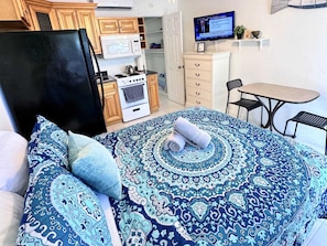 Enjoy a comfortable stay in this cozy room featuring a bed, kitchenette with stove, oven, and refrigerator, and a convenient table with chairs.