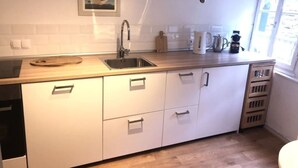 A compact kitchen with white cabinets, a stainless steel sink, and a wooden countertop. - Stylish designer vacation apartment 2, 81sqm, WLAN, SAT, 1st floor (Monschau)