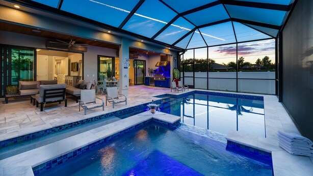 An indoor swimming pool with a glass ceiling, seating area, and a view of the sunset. - Costal Chic Vila w/Private Pool/Spa --5 min from the Beach! (Naples)