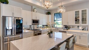 A modern kitchen with stainless steel appliances, white cabinetry, and a marble island. - Costal Chic Vila w/Private Pool/Spa --5 min from the Beach! (Naples)
