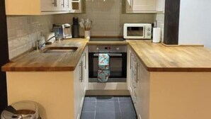 A compact kitchen with a microwave, oven, and sink.