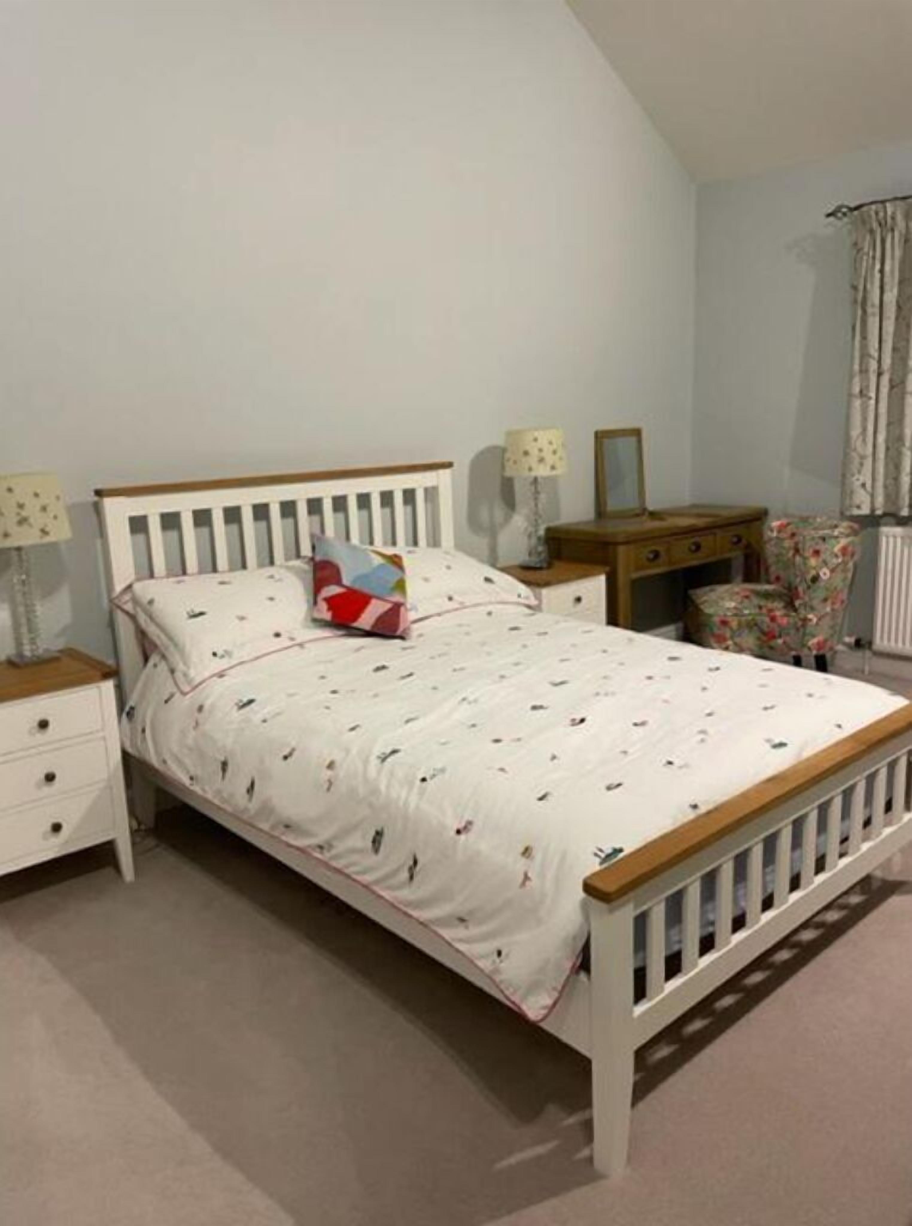 Un dormitorio con una cama individual, una mesita de noche, un aparador, una lámpara y una silla.