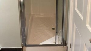 A glass-enclosed shower with a tiled floor and a showerhead.