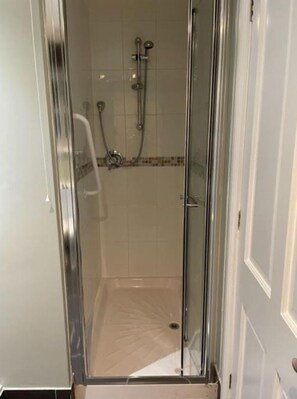 A glass-enclosed shower with a tiled floor and a showerhead.
