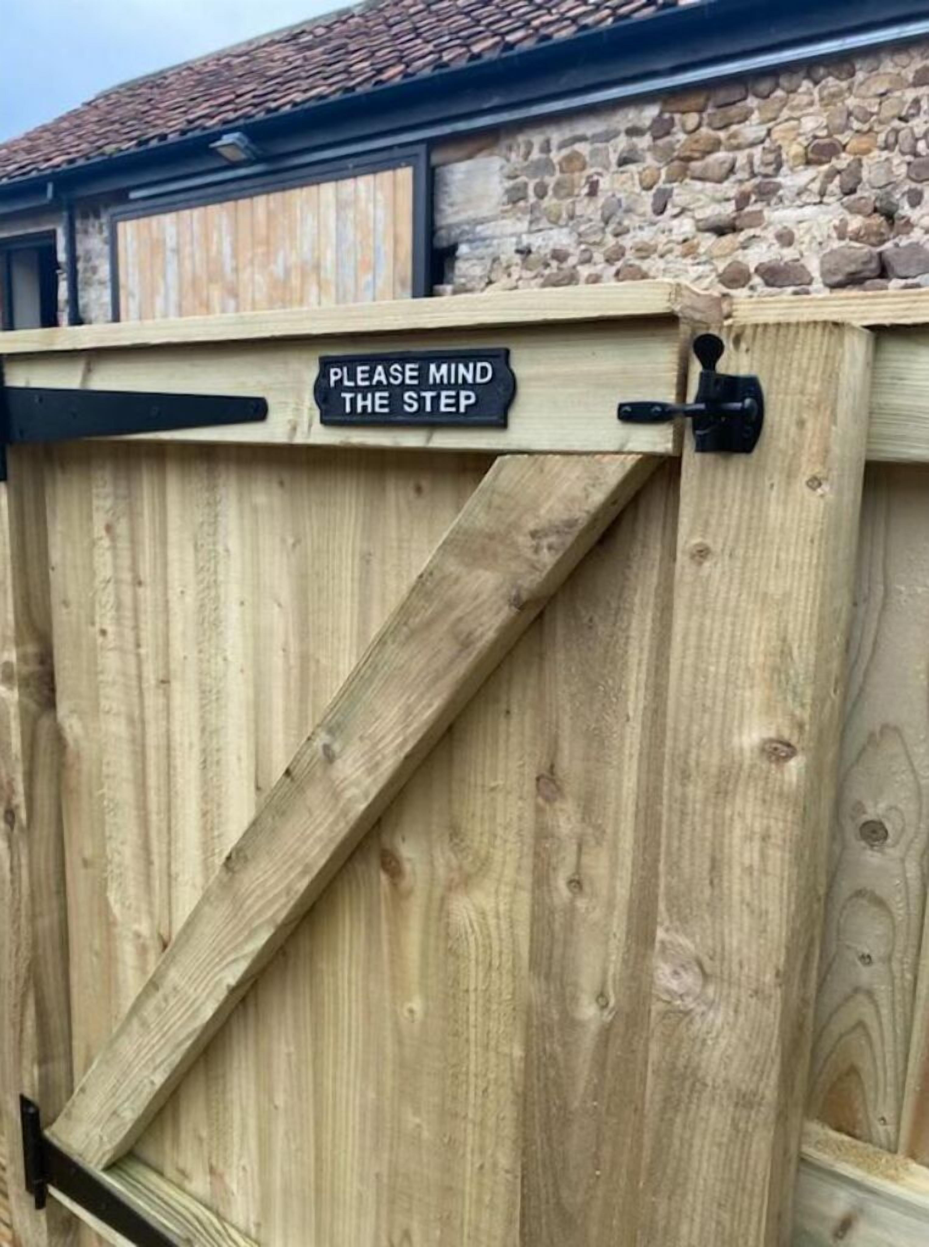 Una puerta de madera con un letrero que dice 'PLEASE MIND THE STEP'.