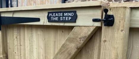 A wooden gate with a sign that reads "PLEASE MIND THE STEP".