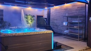 Een moderne spa met een bubbelbad, houten wanden en een wenteltrap.