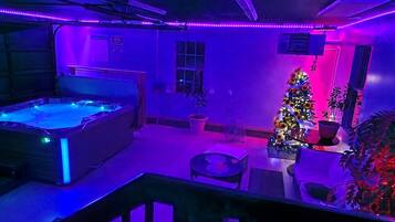 A room with a hot tub, a Christmas tree, and a small table with chairs.
