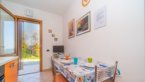 A dining area with a table set for two, a television, and a view of the outdoors. - Appartamento Villa da 2 Fino a 3 Posti Capoliveri (Capoliveri)
